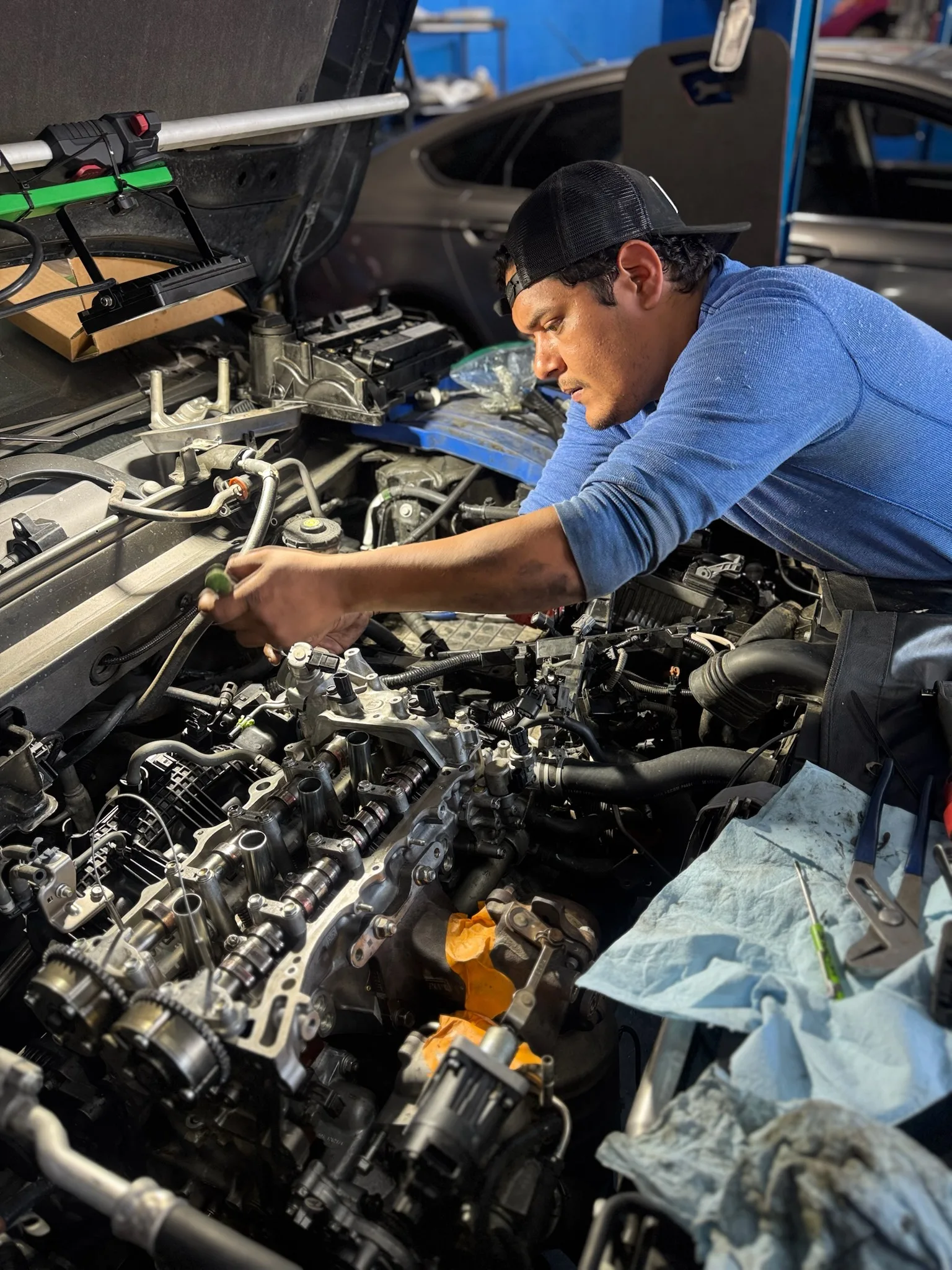 Technician working over an open engine bay with the camshafts and valve train exposed