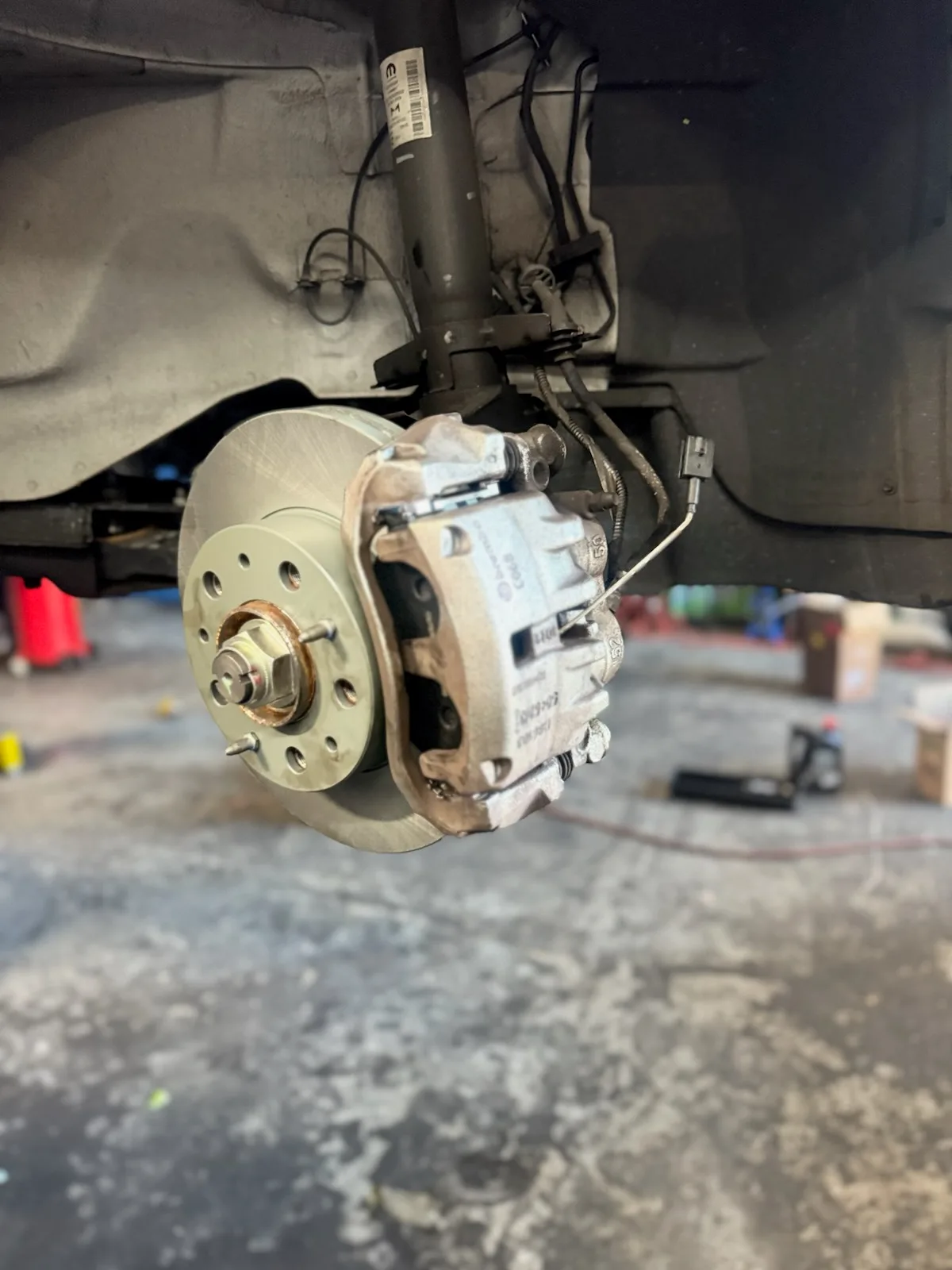 New brake rotor and caliper mounted on a car raised on a lift